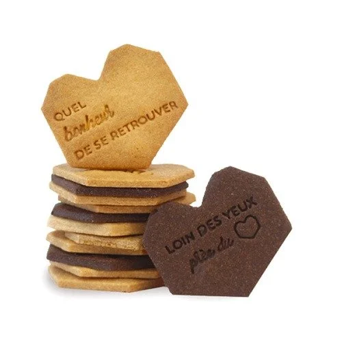 nos retrouvailles Une pile de nos rétrouvailles, certaines marron clair et d'autres marron foncé, entrecoupées de couches de garniture. Le dessus en biscuit personnalisé marron clair porte le texte français qui dit « Quel bonheur de se retrouver », célébrant les rétrouvailles, tandis que le dessus en biscuit personnalisé marron foncé indique « Loin des yeux près du cœur ».