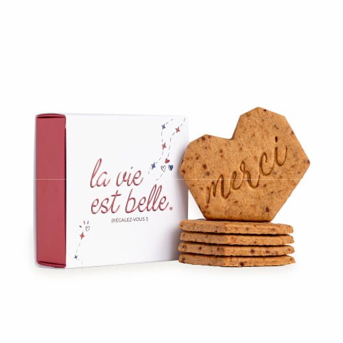 Une boîte blanche et rouge avec l'expression française « la vie est belle » contient plusieurs biscuits en forme de cœur. Le biscuit le plus en avant, gravé d'un délicat « merci », trône fièrement au premier plan. Bien rangées, ces charmantes gourmandises s'offrent à vous devant l'élégant coffret de merci - le coffret de 5 biscuits personnalisés.