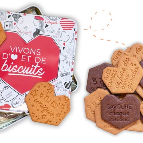 Une boîte en fer blanc ouverte de l'extraordinaire goûter, contenant un assortiment de biscuits en forme de cœur géométrique ornés de messages positifs et ludiques pour le goûter des enfants. Les biscuits sont inscrits avec des pensées positives telles que « SAVOURE chaque instant » et « tu es unique ». Parfait pour favoriser le développement de l'estime de soi des enfants.