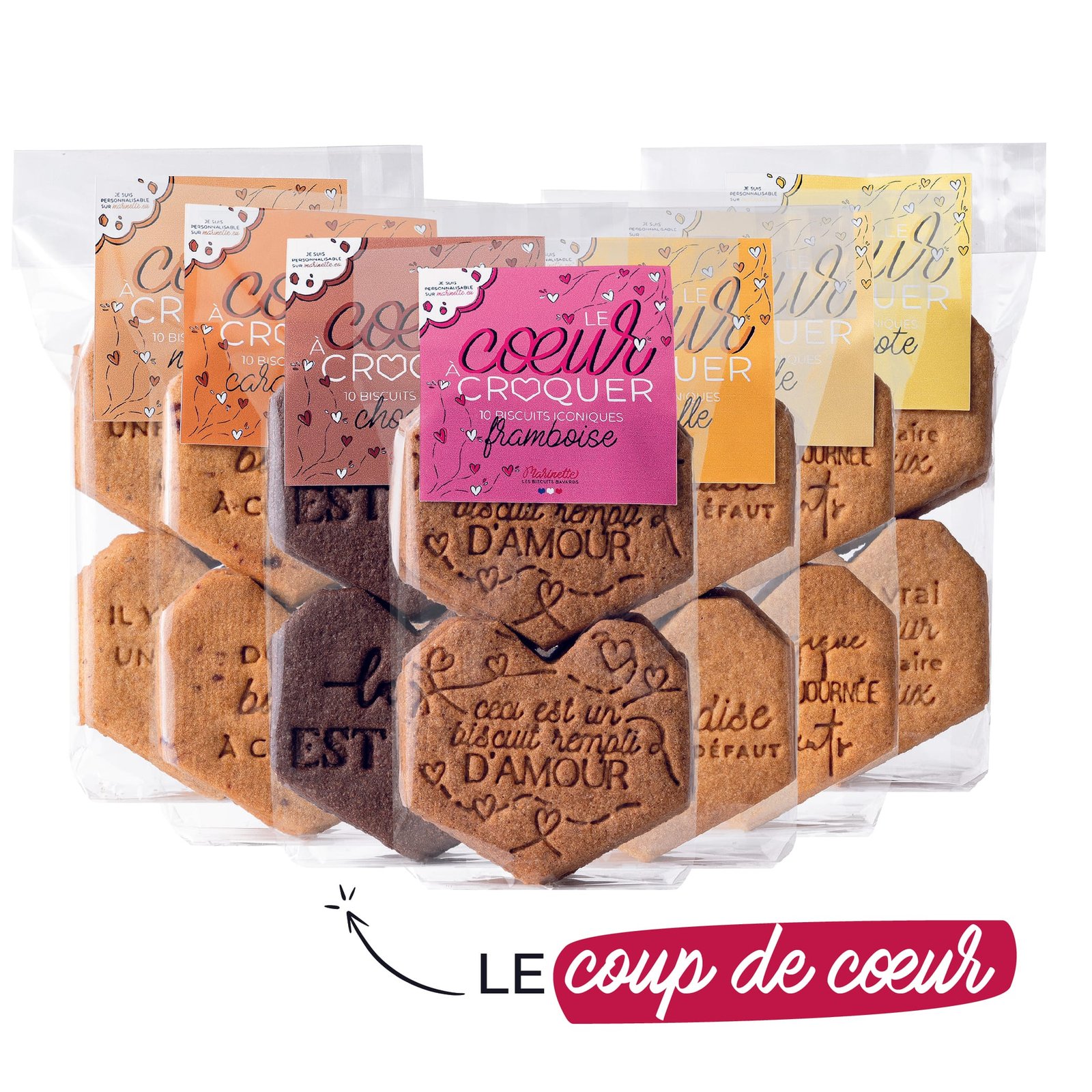cœurs à croquer – le pack Cinq paquets de cœurs à croquer biscuit personnalisé - le pack, chacun avec une forme de cœur, des étiquettes colorées uniques - dont une variante mirabelle - et le texte français sont affichés ensemble. En dessous, "Le coup de cœur" apparaît avec un soulignement rose et un symbole de cœur.